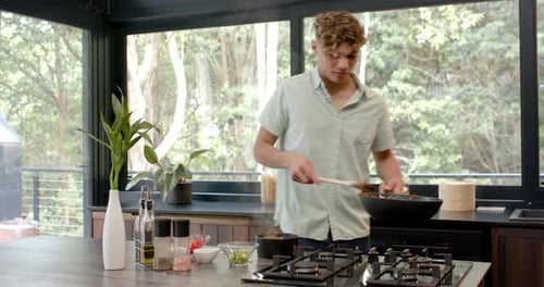 Young Adult Cooking Noodles in Modern Kitchen