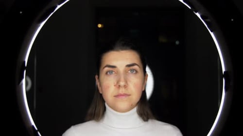 Woman Puts on Glasses in Front of Ring Light