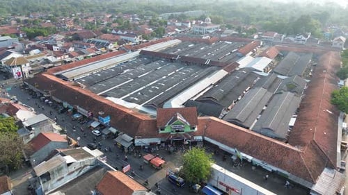 Aerial view of a vibrant market with bustling stalls and buildings, in Comal Pemalang City