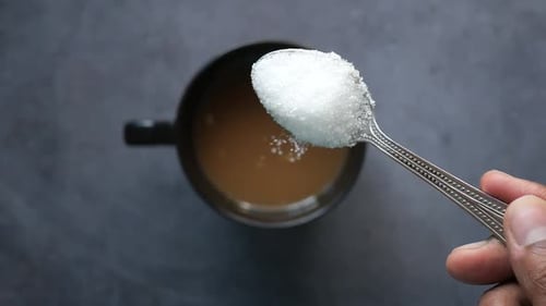 Slow Motion of Pouring White Sugar in a Coffee Cup Top View