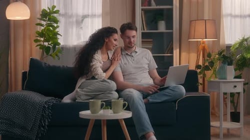 Couple Relaxing on Sofa with Laptop at Home