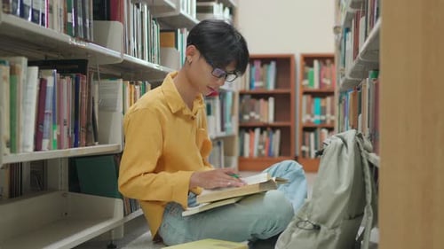 Junger asiatischer Universitätsstudent liest in einer Bibliothek