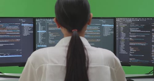 Asian Woman Developer Thinking While Write Code With Multiple Computer Screens In Green Screen