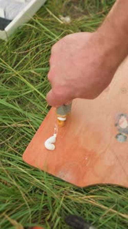 Artist's Hand Pouring Paint on Palette in Grassy Field