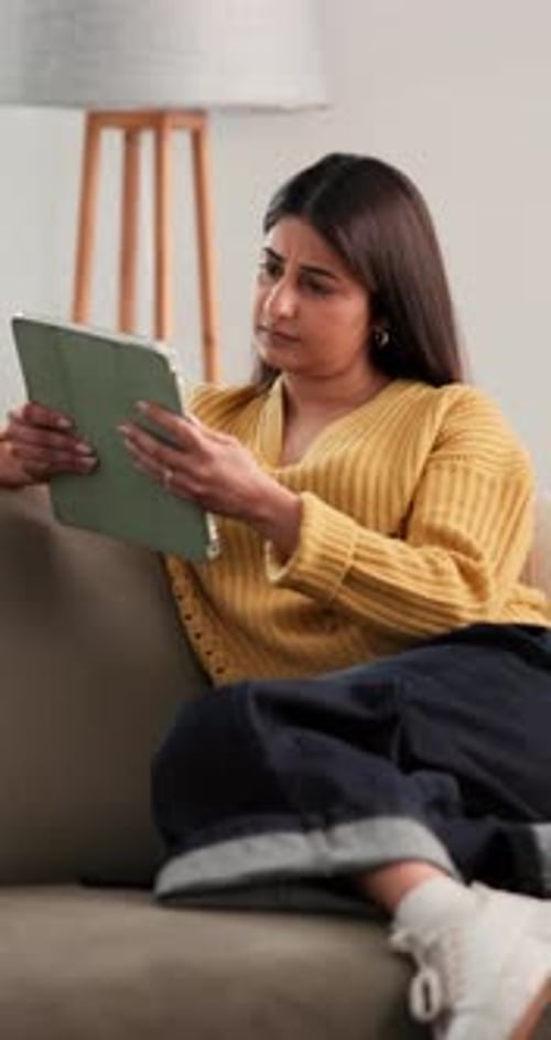 Woman Relaxing on Couch Using Tablet Indoors