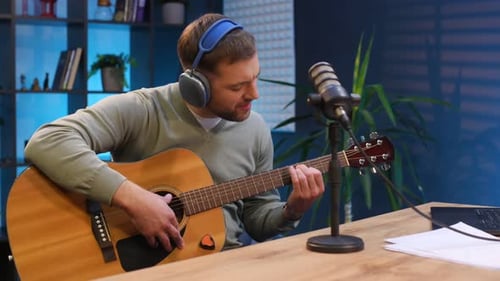 Songwriter with acoustic guitar. Man with microphone in the studio, conception of podcast.
