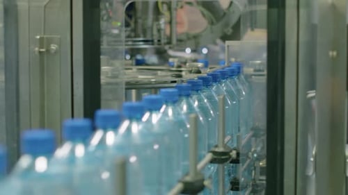 Conveyor Processing Delivery of Plastic Bottles with Water at Beverage Plant