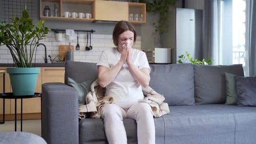 Pregnant Woman Suffering from Cold on Couch Indoors