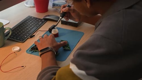 Adult Working on Circuit Board with Soldering Iron