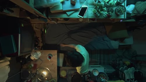 Top View of Asian Person Lying Down to Watch TV in Shoebox Flat