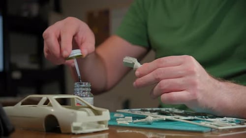 Homme assembleur modèle en plastique de voiture dans une pièce à table selon les dessins et les instructions