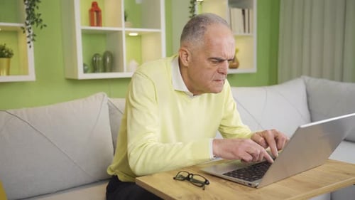 Senior Man Typing on Laptop at Home