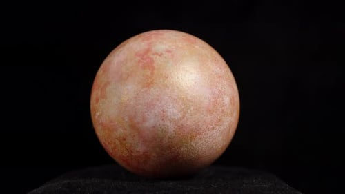 A single marbled Easter egg with subtle pink and gold hues, set against a dark background
