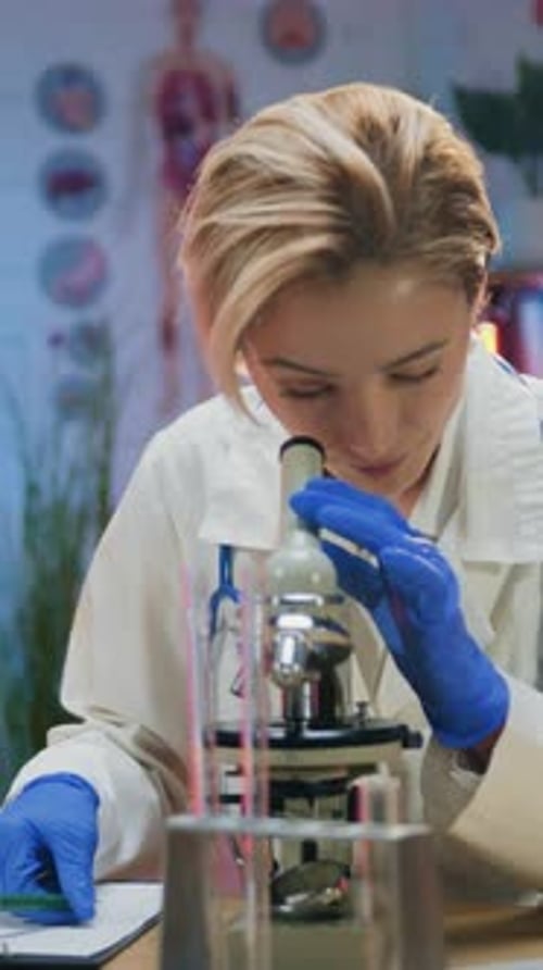 Woman Examines Sample with Microscope in Medical Lab