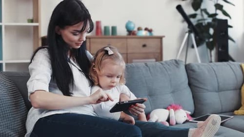 Mother and child sitting looking at tablet together
