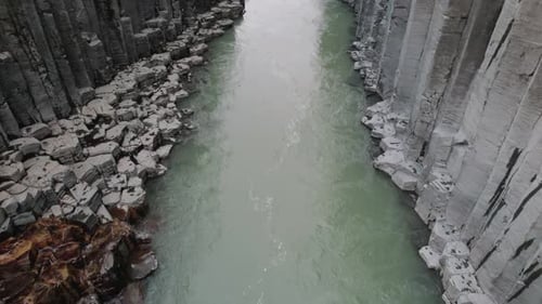 Drone flight with tilt up through beautiful Studlagil Canyon in Iceland.