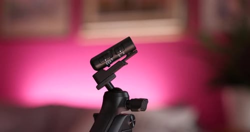 Microphone sans fil monté sur trépied avec fond bokeh rouge. Orbit Motion Shot