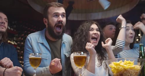 Caucasian Male and Female Friends Cheering Up in Bar When Watching Sport Game Men and Women Clapping