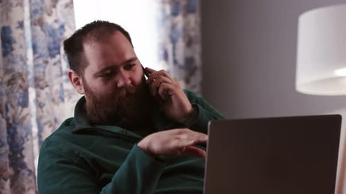Man Talking on Phone While Using Laptop