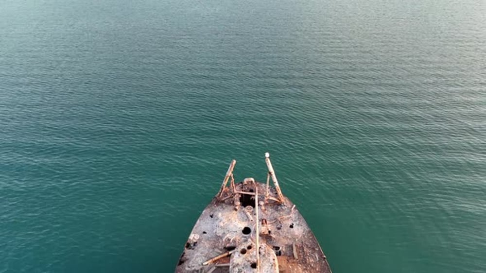 Poros Island,Aerial view backwards and over a rusty sunken ship,half is ...