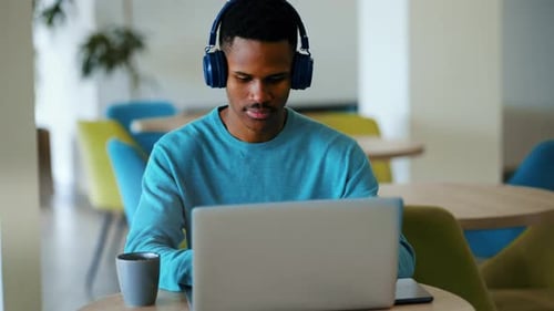 Focused Young Adult Working on Laptop with Headphones