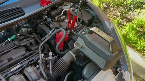 Charging Car Battery with Jumper Cables in Engine