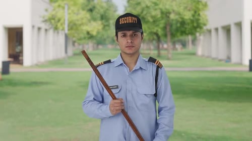 Security Guard Stands Holding Wooden Stick