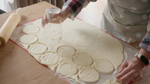 Making Cookies: Woman cutting dough circles for cookies.