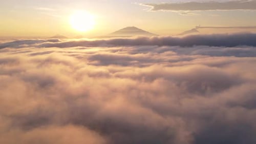 Aerial hyperlapse sea of clouds and sun rising on the horizon with mountains.