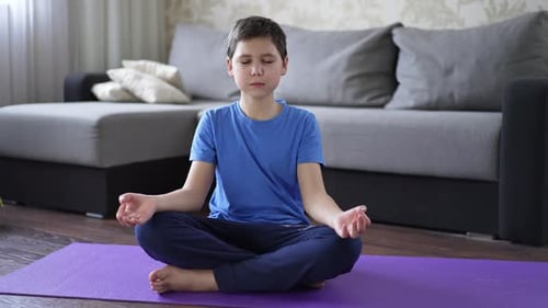 Boy Meditating on Yoga Mat at Home