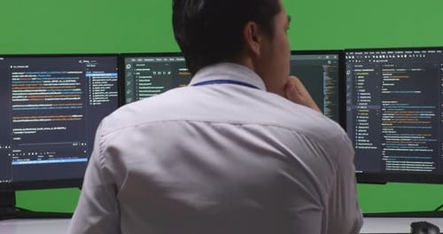 Back View Developer Thinking While Write Code With Multiple Screens In Green Screen Studio