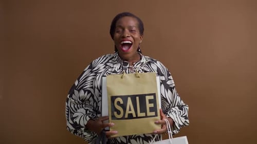 Woman Smiling and Holding Sale Shopping Bags