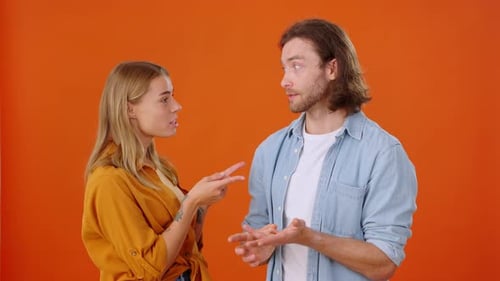 Young Adults Talk and Gesture on Orange Background