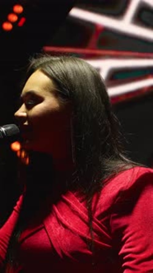 Talented Woman Singing Into Microphone on Stage at Night