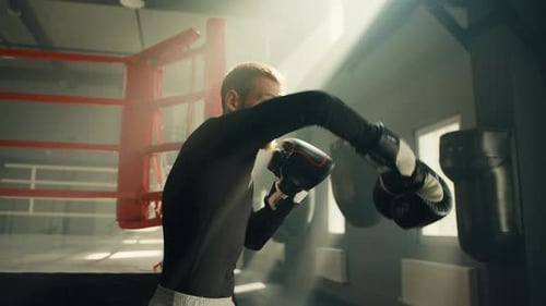 Young Athletic Boxer Performing Shadow Boxing Wearing Boxing Gloves in Gym