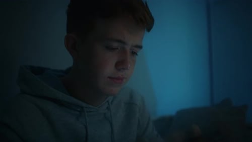 Teen Focused on Mobile Phone in Dark Room