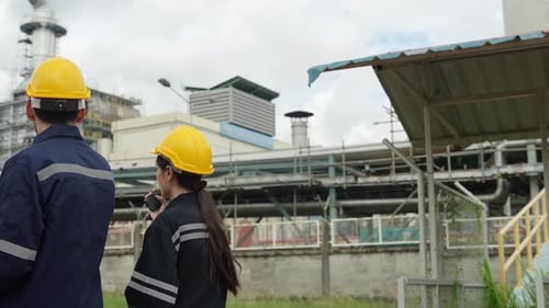Safety inspection of industrial pipeline system by worker in bright safety gear in sunny weather