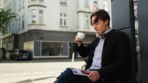 Stilvoller junger Mann genießt Kaffeepause mit Magazin in der Hand
