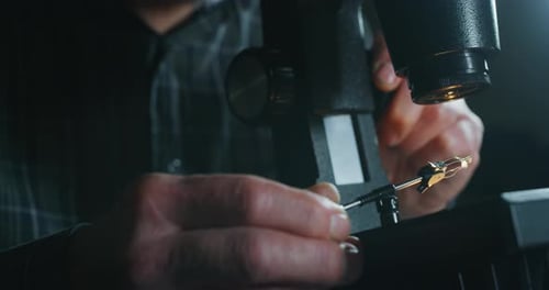 Slow motion close up of experienced goldsmith controlling a quality of diamond stone, selected for