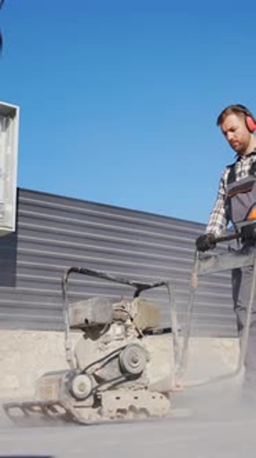Man Operating a Plate Compactor on Asphalt