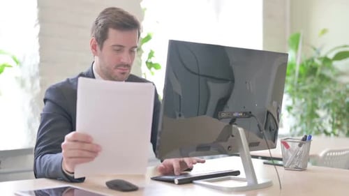 Man Works with Documents and Computer in Office
