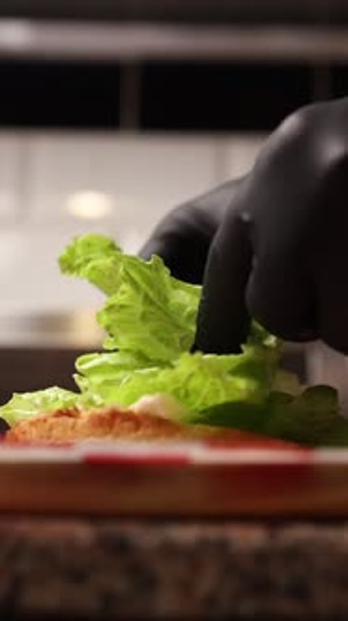 Gloved Hand Assembles Sandwich With Fresh Green Lettuce