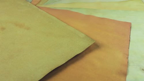 A fan of rotating handmade paper sheets showcases a palette of muted terracotta, olive green, bronze