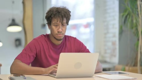 Young Adult Smiles While Working at Laptop