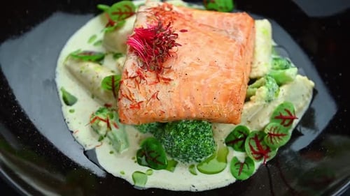 Salmon dish with broccoli and sauce served in a restaurant at dinner time.