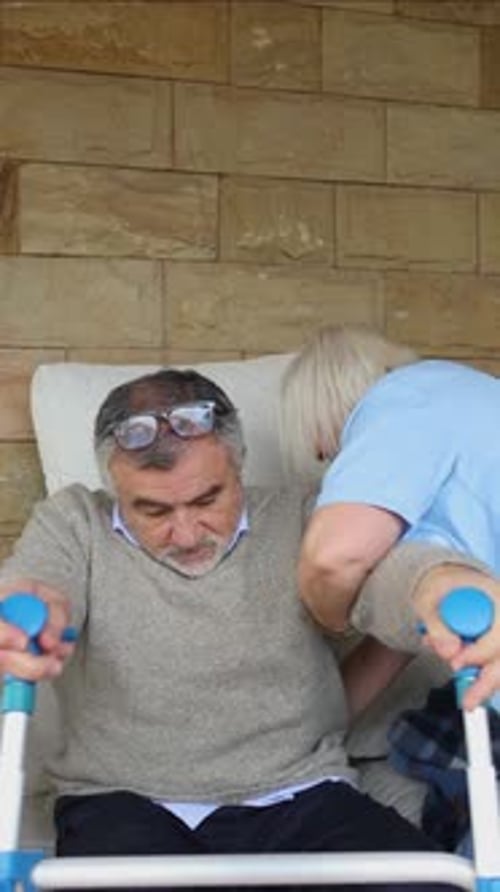 Senior Man Assisted with Walking Aid by Caregiver