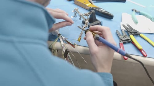 Technician Soldering Wires on a Workbench Close Up