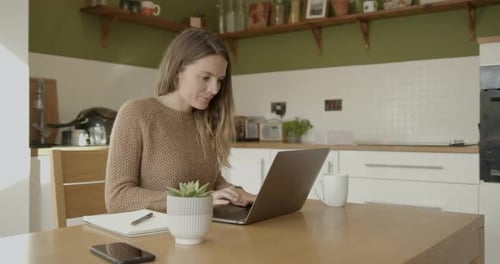 Woman Working at Laptop in Bright Kitchen