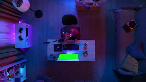 Ansicht von oben auf Mädchen mit Kopfhörern beim Streamen eines Spiels auf dem PC mit Chroma Key Green Screen Talking