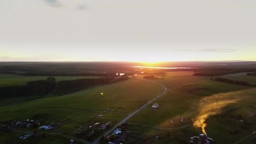 Stunning Aerial View of a Beautiful Sunset Over Expansive Green Fields and Hills Nearby Stock Clip